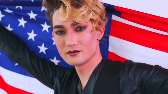 Non Binary Portrait of Asian Man with Luxurious Blonde Hair and Gorgeous Makeup Wawing Usa Flag