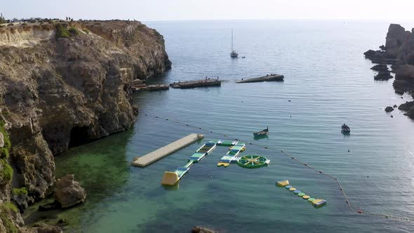 Sailboat near an aquatic playground in a sea lagoon with caves,aerial.