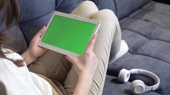 The Girl is Holding a Tablet with a Green Screen