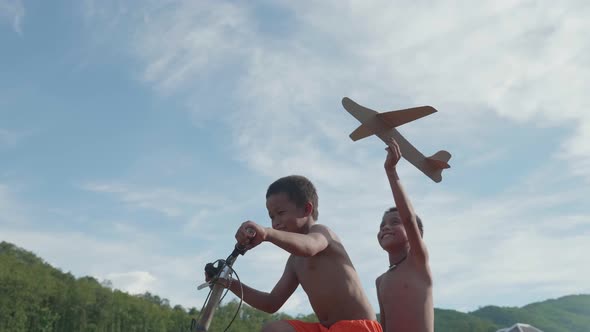 Happy Rural Kids Riding Bike And Playing With Toy Airplane 