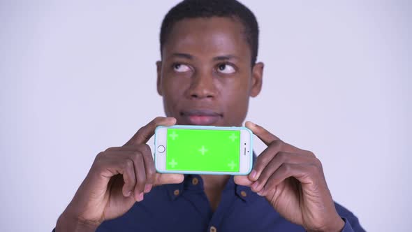 Face of Young Happy African Businessman Thinking While Showing Phone