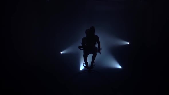 Two Acrobats in the Air on Stage. Black Smoke Background. Silhouette. Slow Motion