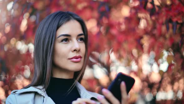 Closeup Face of Woman Chatting Use Smartphone at Red Tree Autumn Foliage Bokeh