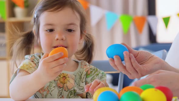 Baby Girl and Mother Beating Easter Eggs at Home