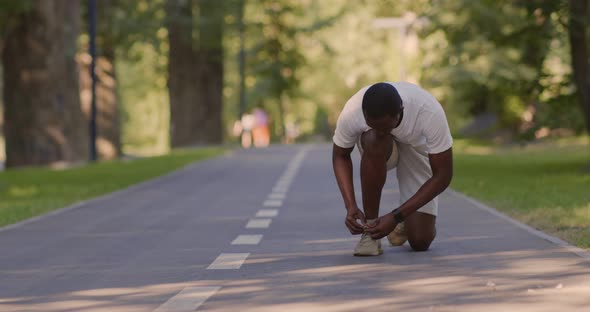 African American Guy Tying Up Laces on Sneakers During Run Workout