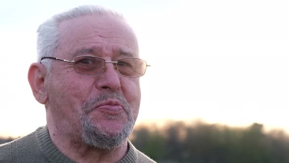 Sad Man with Gray Hair Talking in the Garden at Sunset