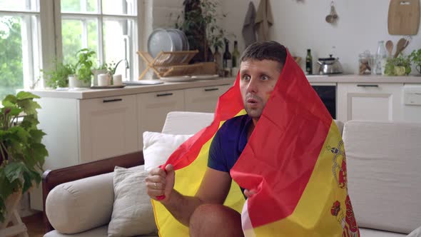 A Spanish Football Fan Watches TV at Home with the Flag of Spain