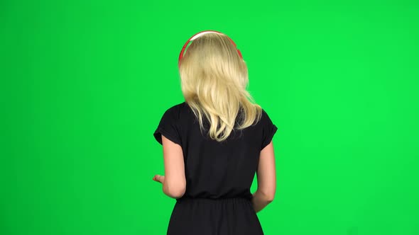 Back View of Woman Walks in Big Red Headphones and with a Smartphone and Dancing