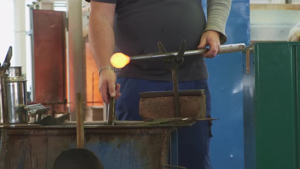 Worker Operates with Hot Glass Workpiece on Blowpipe in Shop