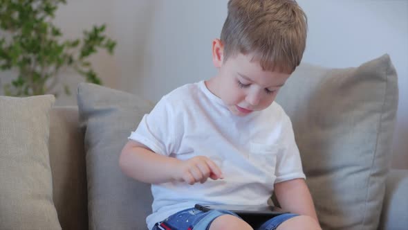 Curious Cute Boy Preschool Child Using a Digital Tablet Technology Device Looks telephone.Plays in