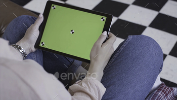 Young woman using black tablet device with green screen. Stock footage. Woman holding tablet