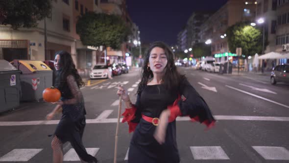 Two Pretty Girls Walking In An Empty Road Wearing Halloween Costumes  Moving Medium Shot