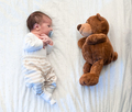 Cute little baby laying with his teddy bear on bed - PhotoDune Item for Sale