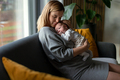 Loving mother hugs her little baby at home on sofa - PhotoDune Item for Sale