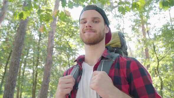 Close-up Portrait of Confident Handsome Male Hiker Standing in Sunny Forest and Smiling at Camera