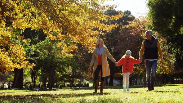 mother dad and daughter walking hand in hand outdoors