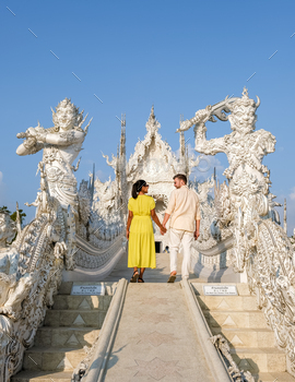nd, Wat Rong Khun, aka The White Temple, in Chiang Rai, Thailand. Asian women and Caucasian men visit a temple with a blue sky