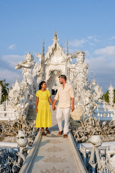 nd, Wat Rong Khun, aka The White Temple, in Chiang Rai, Thailand. Asian women and Caucasian men visit a temple with a blue sky