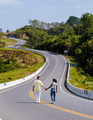 A couple walking at a curved road in the mountains of Nan Thailand, Road nr 3 country road  - PhotoDune Item for Sale