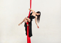 Slim young woman performing standing pose on aerial red silks - PhotoDune Item for Sale