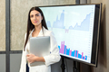 Young businesswoman standing near screen with charts - PhotoDune Item for Sale