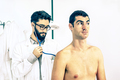 Young hipster primary doctor at work auscultating male patient in private clinic - PhotoDune Item for Sale