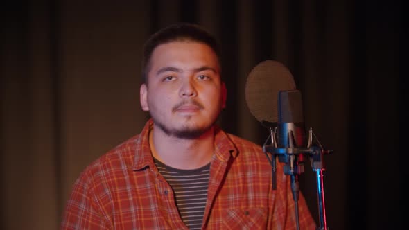 A Man in a Plaid Shirt Sings Into the Microphone