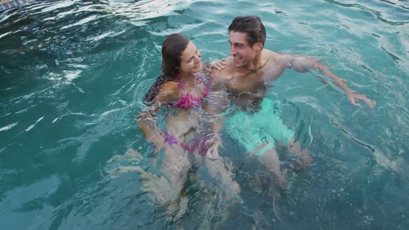 Happy Caucasian couple enjoying the pool during a sunny day