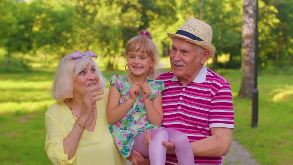 Little Cute Granddaughter Child Embracing with Her Grandmother and Grandfather Family Couple in Park