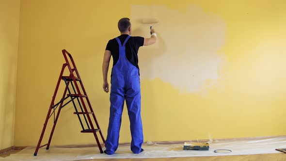 Painter paints on yellow wall