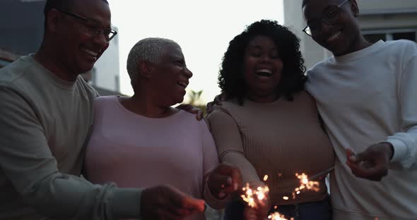 Happy african family celebrate outdoor with firework sparklers at home - Love and lifestyle concept