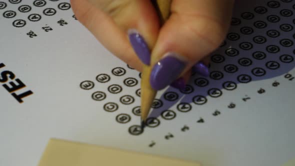 Female student checking test answer boxes with a pencil. Filling in answer sheet for test