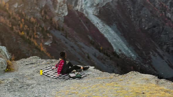 Woman Enjoy the Sunset Sitting on Top of a High Mountain