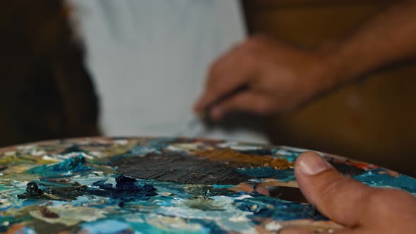 Artist Painter Mixing Brown Oil Paint with Brush on Palette alt