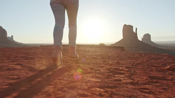 Young Woman in Hiking Boots and Blue Jeans Running on Top of Mountain at Sunset