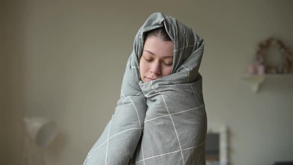 A young woman is basking, wrapped in a blanket. The woman just woke up