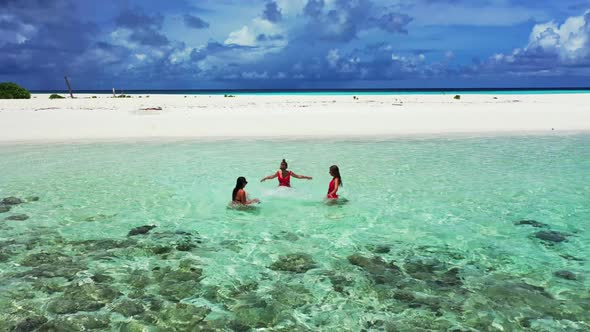 Girls happy together on beautiful coastline beach adventure by clear lagoon with white sandy backgro