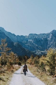 a narrow gravel road towards rocky mountains with your space for text above