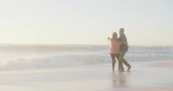 Smiling senior african american couple holding hands and dancing on sunny beach