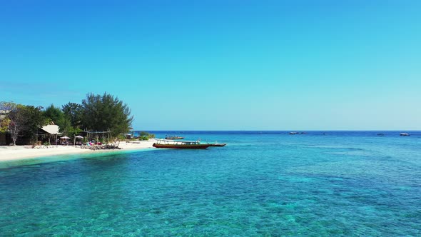 Bright blue sky reflecting on vibrant crystal water of turquoise lagoon washing white sand of exotic