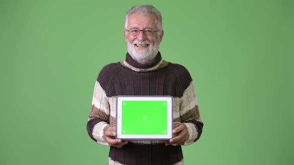 Handsome Senior Bearded Man Wearing Warm Clothing Against Green Background