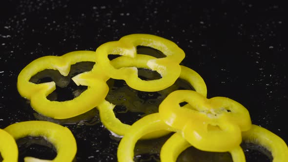 Rings of Yellow Bell Pepper Falling on a Wet Black Surface