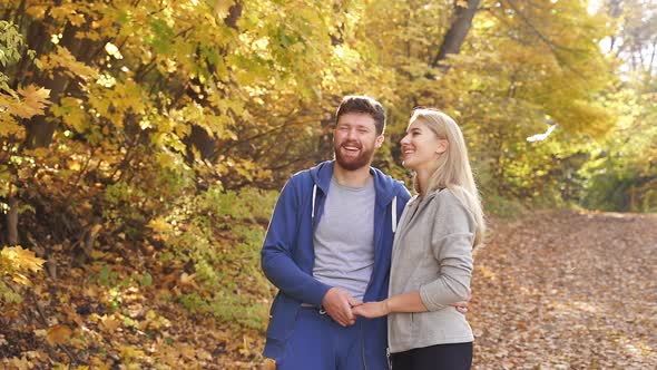 Happy Sports Couple Having Fun in the Forest Standing in Contemplation of Bright Autumn Yellow