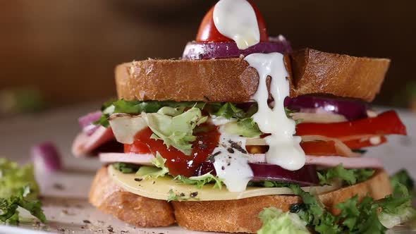 Pouring Ketchup and Mayonnaise sauce over one Sandwich