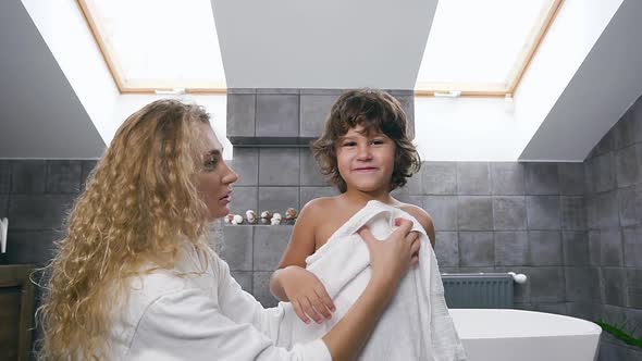 Woman Wiping Her Son's Body with Towel while Boy Posing to the Camera and Showing His Streght