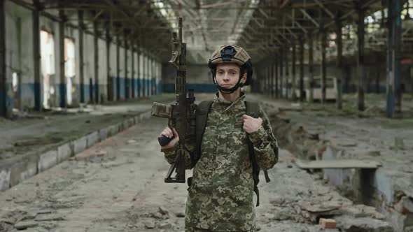 Female Soldier in Uniform with Weapon Posing on Old Factory