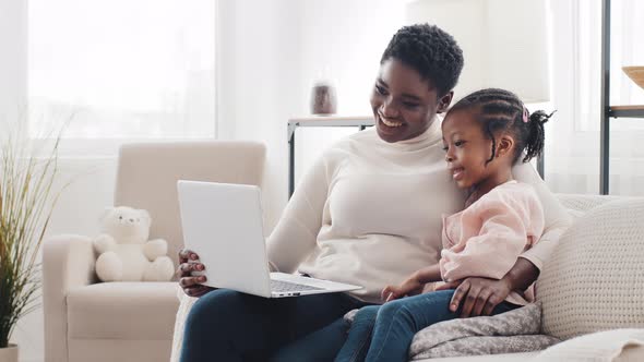 Afro American Mother Mom Woman and Little Black African Girl Daughter Child Kid Sitting at Home