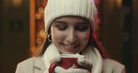 Young woman drinking from a mug.