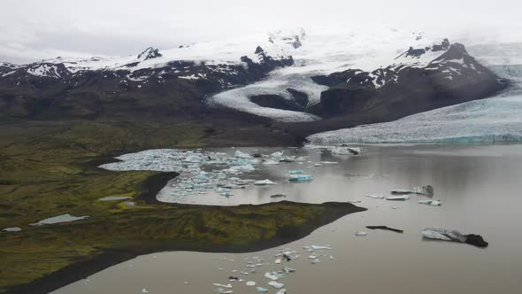 Glacier in Iceland with blue ice in water with drone video moving forward.