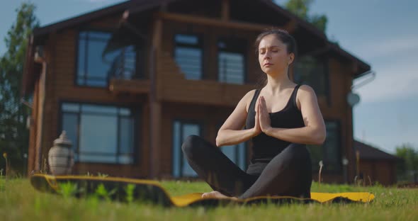 Young Woman Practicing Yoga on Plot of Country House